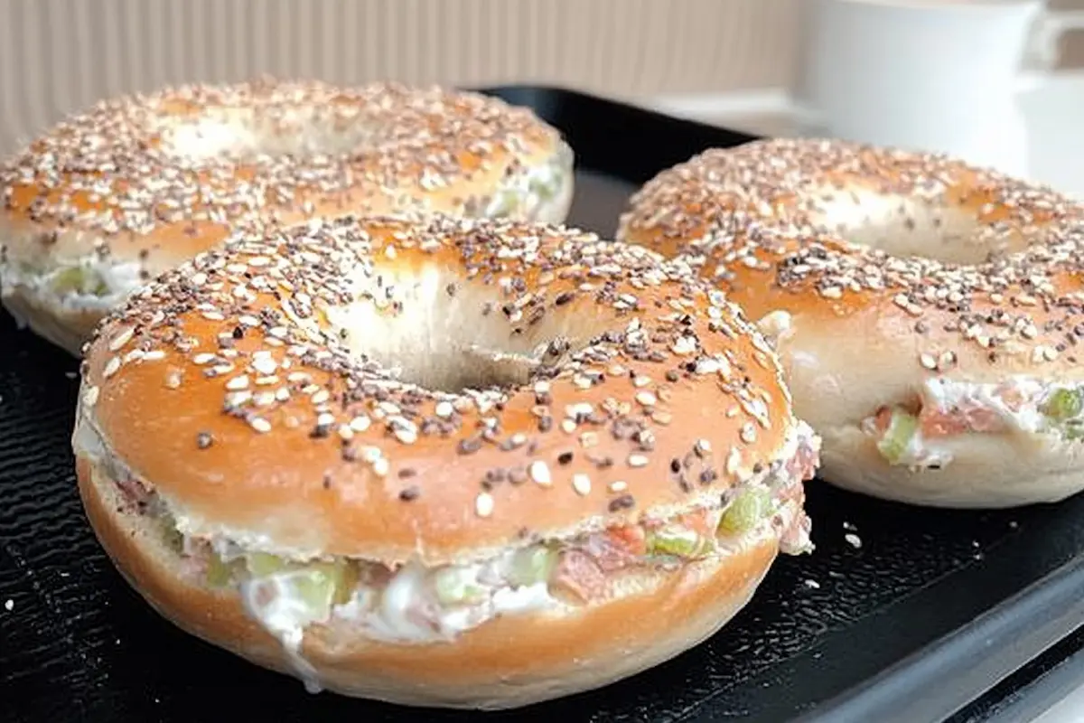 Three everything bagels filled with cream cheese, diced salmon, and green onions, served on a tray as an example of a better bagel breakfast option.