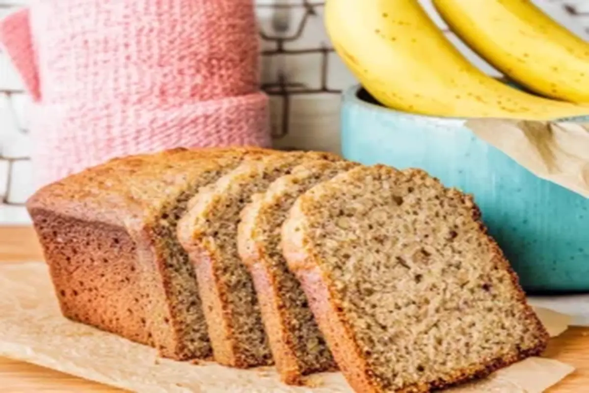 Freshly baked butter-free banana bread sliced and displayed with ripe bananas in the background, emphasizing its healthy and delicious appeal.